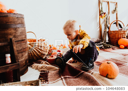 Cool trendy hipster boy 2 years old wears black posing at the decorated photozone of autumn decor with beautiful bright autumn leaves, pumpkin, apples. 104648083