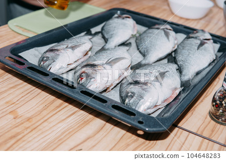 Raw Dorado fish for baking in the oven. Cooking Dorado fish in the cooking class. Raw fish, selective focus. Home food, cooking at home. 104648283