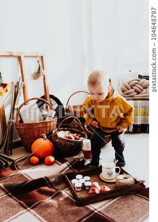 Cool trendy hipster boy 2 years old wears yellow jacket posing at the decorated photozone of autumn decor with beautiful bright autumn leaves. 104648797