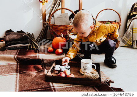 Cool trendy hipster boy 2 years old wears yellow jacket posing at the decorated photozone of autumn decor with beautiful bright autumn leaves. Cool trendy hipster boy 2 years old wears yellow jacket posing at the decorated photozone of autumn decor with beautiful bright autumn leaves. 104648799