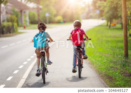 Two boys with backpacks on bicycles going to school. Two boys with backpacks on bicycles going to school. 104649127