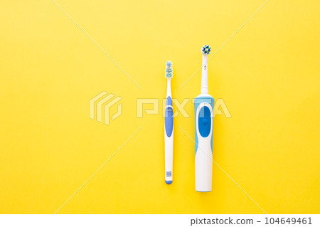 Electric and analog toothbrush in blue on a yellow background Electric and analog toothbrush in blue on a yellow background 104649461