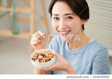年輕女子吃混合堅果吃喝圖像 104649889