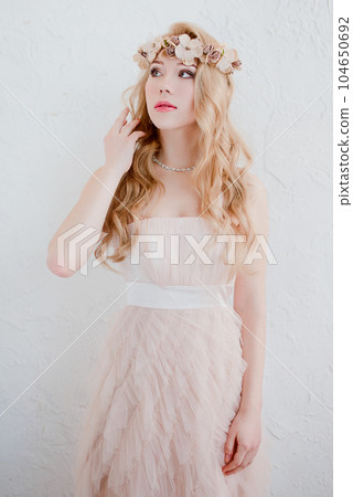 picture of young blonde woman wearing wreath of flowers, spring tender and romantic portrait, fashion retouched shot 104650692