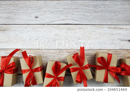 Gift boxes with red ribbon on wooden background Gift boxes with red ribbon on wooden background 104651469