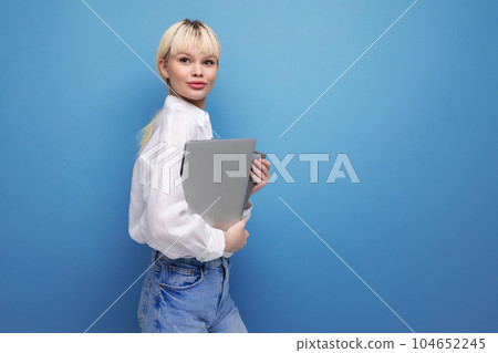 young successful smart blond female student dressed in a white blouse with a laptop in her hands young successful smart blond female student dressed in a white blouse with a laptop in her hands 104652245