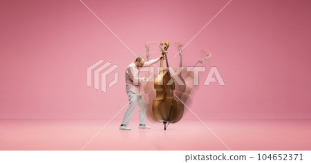 Creative collage. Talented, emotional young man with stylish moustaches playing double bass against pink studio background 104652371
