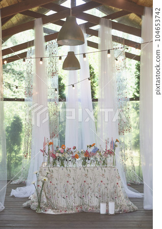 Floristics. Floral decoration of the wedding in pastel colors. Many flowers in different vases and vessels 104653742