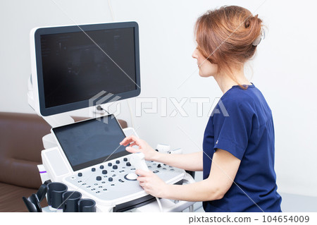 Doctor woman doing ultrasound scanning diagnostic of thyroid gland sitting in office in clinic. 104654009