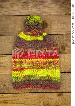 Handmade wool knitted winter colored hat, on wooden background 104655104