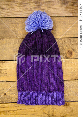 Handmade wool knitted winter blue hat on wooden background Handmade wool knitted winter blue hat on wooden background 104655107