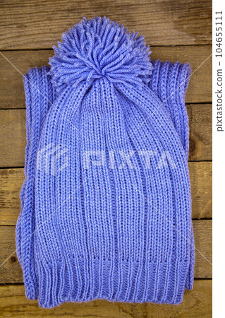 Handmade wool knitted winter blue hat and scrarf on wooden background 104655111