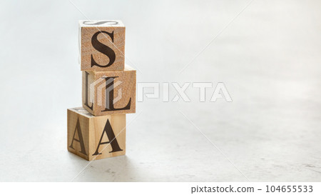 Pile with three wooden cubes - letters SLA meaning Service Level Agreement on them, space for more text / images at right side. 104655533