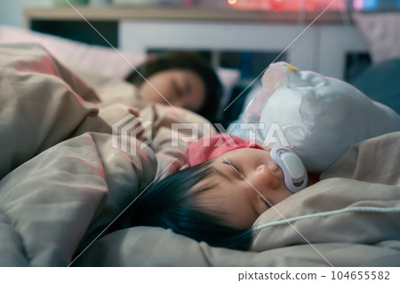 Asian little baby girl sucking pacifier while sleep on bed at home. 104655582