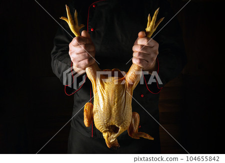 Raw rooster in the chef hand. Cock presentation before preparing a delicious dish in the restaurant kitchen. Chicken selection before frying. Raw rooster in the chef hand. Cock presentation before preparing a delicious dish in the restaurant kitchen. Chicken selection before frying. 104655842