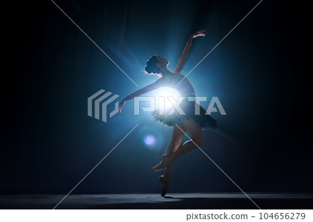 Attractive, artistic, talented young girl, ballerina dancing classical dance, performing against dark blue background with spotlight Attractive, artistic, talented young girl, ballerina dancing classical dance, performing against dark blue background with spotlight 104656279