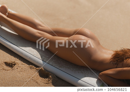 Close-up of Tanned Naked Surf Girl on Surfboard During Beach Relax 104656821
