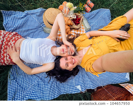 Two friends take a selfie on a blue blanket for an outdoor picnic Two friends take a selfie on a blue blanket for an outdoor picnic 104657950
