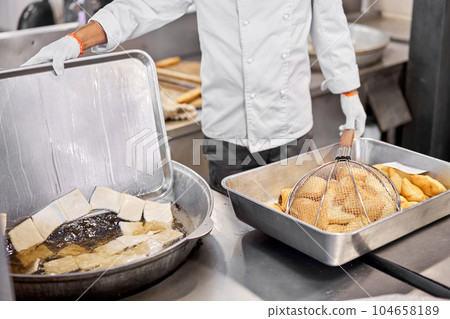 Male cook preparing delicious National Kazakh pastries baursak. street cafe. Fry dough in boiling oil in a frying pan. Male cook preparing delicious National Kazakh pastries baursak. street cafe. Fry dough in boiling oil in a frying pan. 104658189