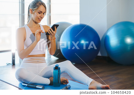 Girl on Yoga Mat with Phone 104658420