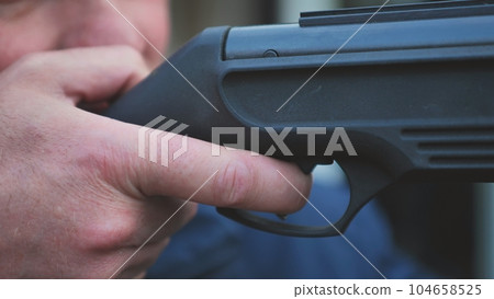A man firing an air gun. Close-up of her hands. A man firing an air gun. Close-up of her hands. 104658525