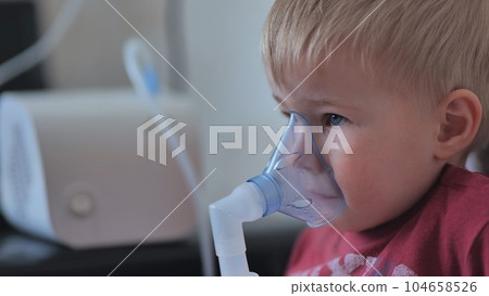 Funny boy breathing through an inhaler mask. Funny boy breathing through an inhaler mask. 104658526