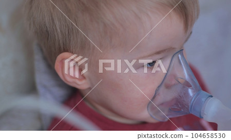 Funny boy breathing through an inhaler mask. 104658530