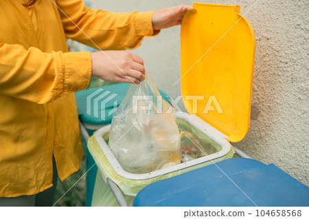 young woman throws garbage bag in the trash sorting waste, female in casual wear, eco-friendly person save planet, environment by pollution contamination. copy space. zero waste 104658568