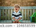 Education Concept. Portrait of happy primery school child boy looking at camera, holding stack of academic books and wearing backpack banner. Back to school. Funny face in glasses screeming from enjoy 104658599