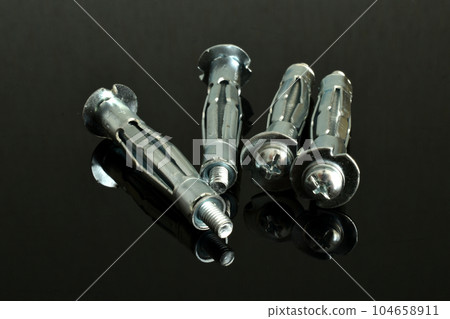 Anchor bolts for fastening on a black background. Anchor bolts for fastening on a black background. 104658911
