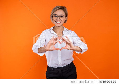 Romantic woman wearing white official style shirt showing heart shape with hands Romantic woman wearing white official style shirt showing heart shape with hands 104659455