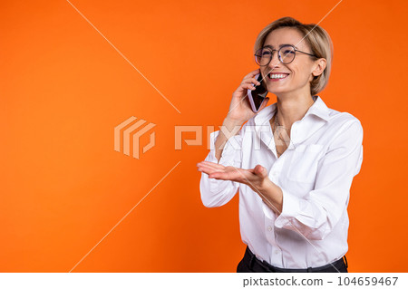 Joyful woman wearing white official style shirt talking on smartphone spreading palms 104659467
