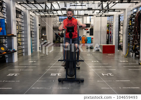 Man in sportswear doing cycling on exercise bikes at the gym, cardio workout. 104659493