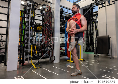 Athletic man warming up and stretching legs before training fitness gym, body care. Athletic man warming up and stretching legs before training fitness gym, body care. 104659825