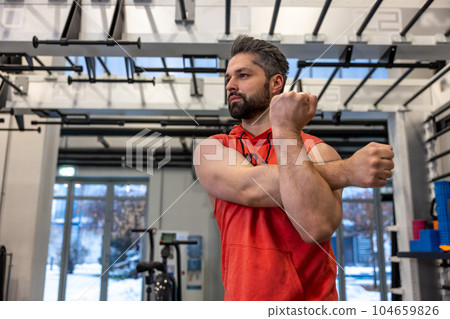 Handsome adult Caucasian man warm up and stretching arms before exercising in fitness gym Handsome adult Caucasian man warm up and stretching arms before exercising in fitness gym 104659826