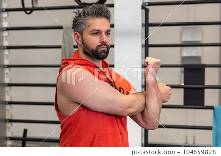 Athletic man warming up and stretching arms before training fitness gym, body care. 104659828