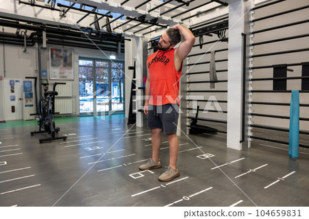 Handsome adult Caucasian man warm up and stretching neck before exercising in fitness gym 104659831