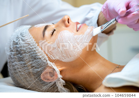 Cosmetologist doing cleansing beauty procedures in clinic, peeling and anti aging. Cosmetologist doing cleansing beauty procedures in clinic, peeling and anti aging. 104659844