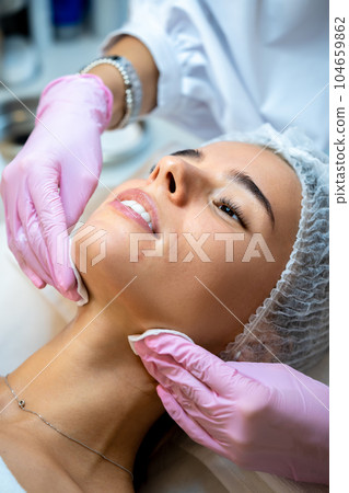Professional woman cosmetologist cleaning customer face, beauty skin care treatment. 104659862