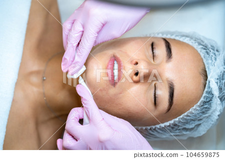 Beautician doctor doing cleansing face procedures to woman in cosmetology clinic. 104659875