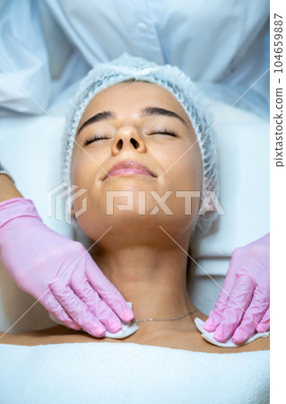 Female beautician doctor cleaning customer skin, make facial massage to patient. 104659887