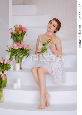 Smiling woman feels joy and happiness, holds a yellow tulip. 104659947