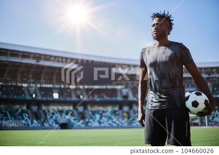 Intense portrait of a football player holding the ball in the stadium 104660026
