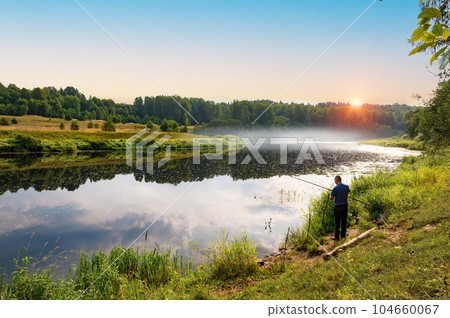In the early summer morning, a fisherman is fishing in the upper reaches of the Volga River. In the early summer morning, a fisherman is fishing in the upper reaches of the Volga River. 104660067