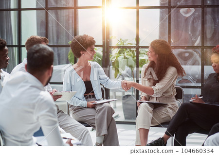 Welcome aboard. Group of business people sitting on a chair while two people shake hands 104660334