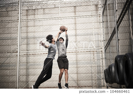 two young asian men playing basketball outdoors two young asian men playing basketball outdoors 104660461