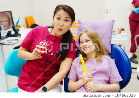 Cheerful pediatric dentist with a patient. training in proper brushing Cheerful pediatric dentist with a patient. training in proper brushing 104662320