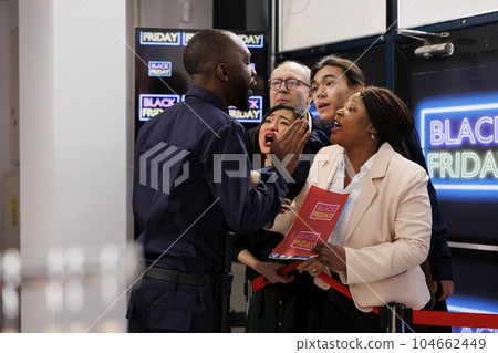 Impatient eager shoppers waiting in line to make Black Friday purchases and get best deals. Crowd of diverse people arguing with security guard at shopping mall entrance, wait for sales Impatient eager shoppers waiting in line to make Black Friday purchases and get best deals. Crowd of diverse people arguing with security guard at shopping mall entrance, wait for sales 104662449