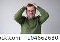 The young man with a panic attack is desperately tearing his hair on his head 104662630