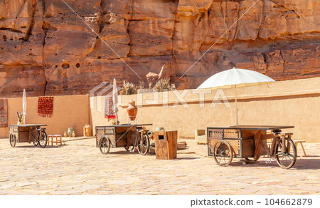 Al Ula old arabic town souk market street with wheeled trading stalls and umbrellas, Medina province, Saudi Arabia Al Ula old arabic town souk market street with wheeled trading stalls and umbrellas, Medina province, Saudi Arabia 104662879